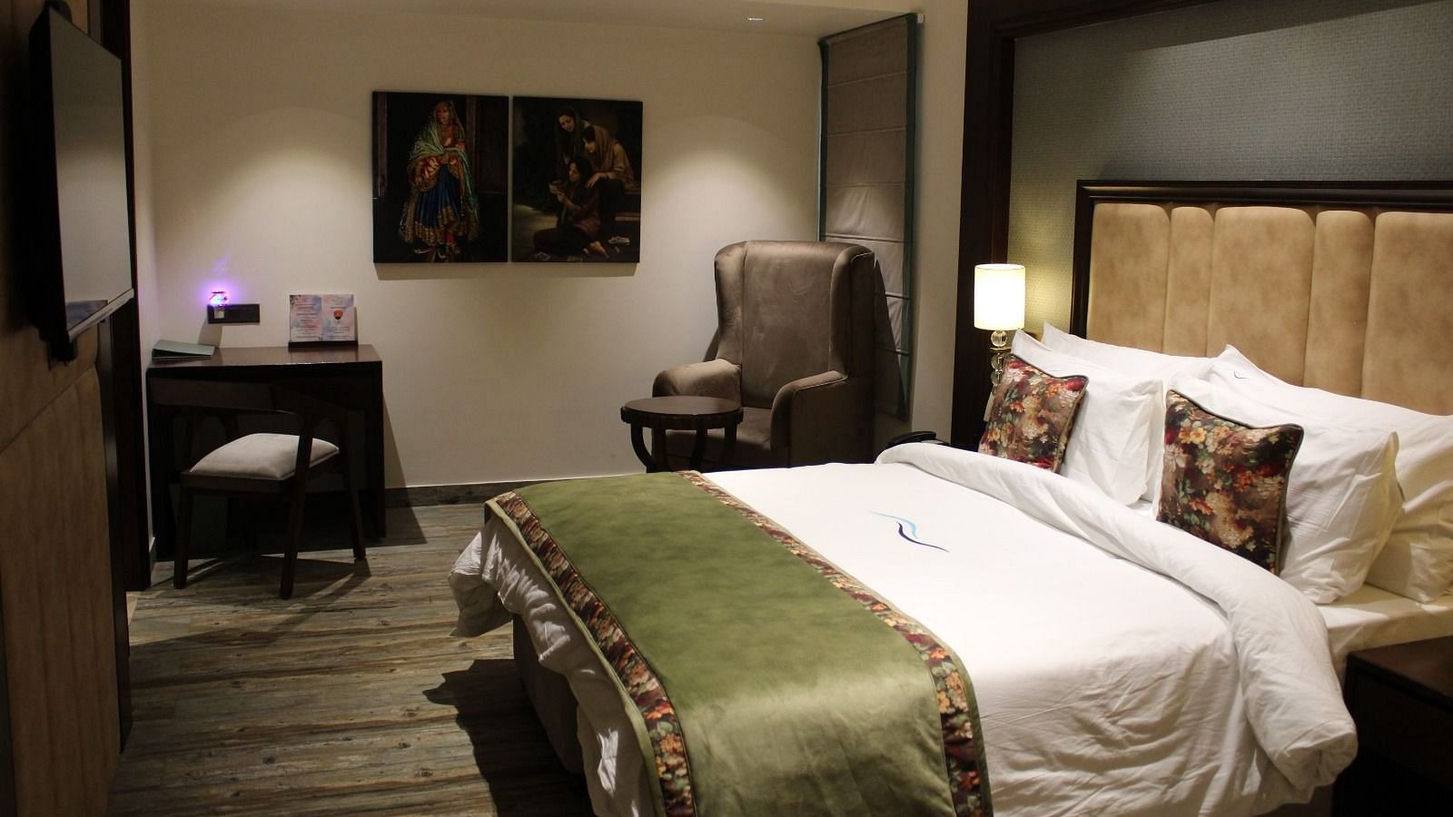Side view of a bedroom featuring a working table, a chair, and portraits adorning the wall at BluSalzz Residence, Amritsar